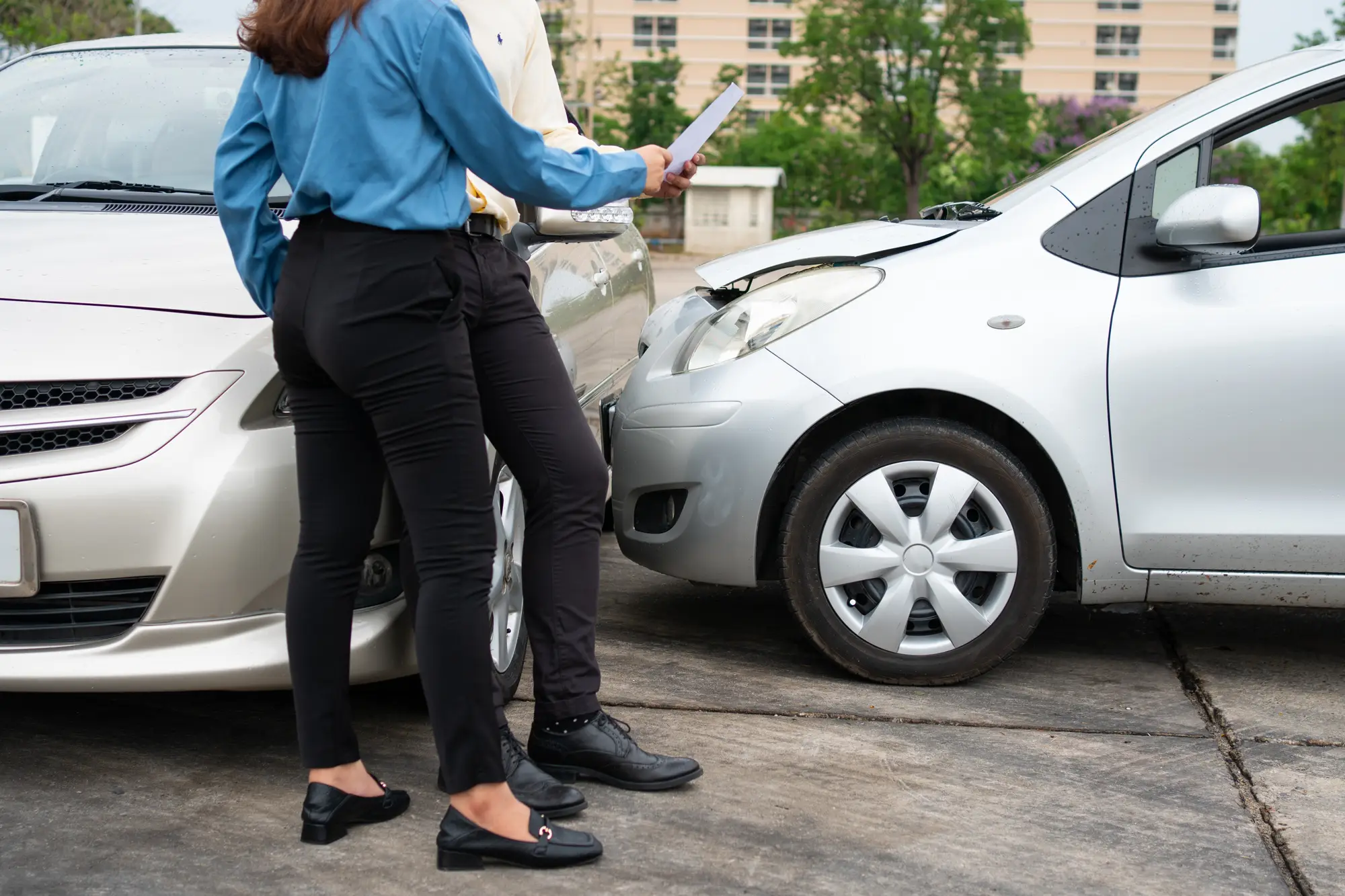 Two Drivers using a smartphone to exchange phone numbers and social media after a car accident.
